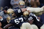 SOUTH BEND, IN - OCTOBER 13:  Members of the Notre Dame Fighting Irish including John Ryan #90, Dwight Stephenson #57 and Terrail Lambert #20 are called for a penalty for excessive celebration as they jump on teammate Brian Smith after Smith intercepted a pass and ran for a touchdown against the Boston College Eagles on October 13, 2007 at Notre Dame Stadium in South Bend, Indiana. Boston College defeated Notre Dame 27-14.  (Photo by Jonathan Daniel/Getty Images)