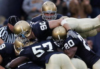 SOUTH BEND, IN - OCTOBER 13:  Members of the Notre Dame Fighting Irish including John Ryan #90, Dwight Stephenson #57 and Terrail Lambert #20 are called for a penalty for excessive celebration as they jump on teammate Brian Smith after Smith intercepted a pass and ran for a touchdown against the Boston College Eagles on October 13, 2007 at Notre Dame Stadium in South Bend, Indiana. Boston College defeated Notre Dame 27-14.  (Photo by Jonathan Daniel/Getty Images)