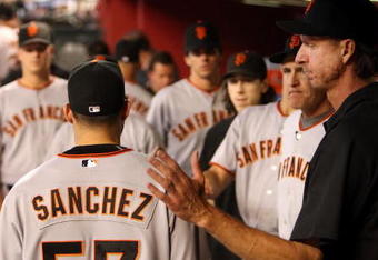 PHOENIX - JUNE 11:  Starting pitcher Jonathan Sanchez #57 of the San Francisco Giants is greeted by Randy Johnson (R) and teammates after being removed from the major league baseball game against the Arizona Diamondbacks at Chase Field on June 11, 2009 in Phoenix, Arizona.  The Diamondbacks defeated the Giants 2-1. (Photo by Christian Petersen/Getty Images)