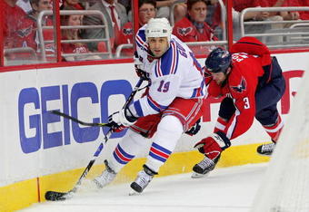 WASHINGTON - APRIL 28: Scott Gomez #19 of the New York Rangers skates the puck past Tom Poti #3   of the Washington Capitals during Game Seven of the Eastern Conference Quarterfinal Round of the 2009 Stanley Cup Playoffs on April 28, 2009 at the Verizon Center in Washington,  DC.  (Photo by Len Redkoles/Getty Images)