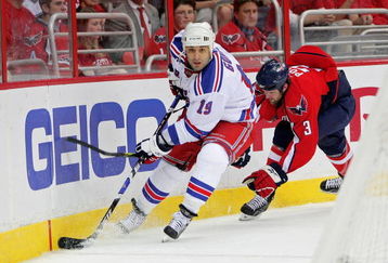 WASHINGTON - APRIL 28: Scott Gomez #19 of the New York Rangers skates the puck past Tom Poti #3   of the Washington Capitals during Game Seven of the Eastern Conference Quarterfinal Round of the 2009 Stanley Cup Playoffs on April 28, 2009 at the Verizon Center in Washington,  DC.  (Photo by Len Redkoles/Getty Images)