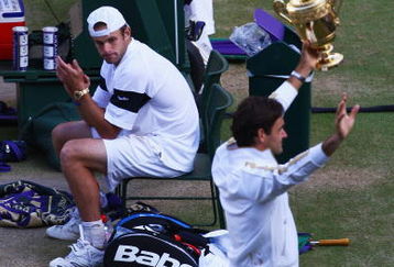 WIMBLEDON, ENGLAND - JULY 05:  Andy Roddick of USA looks despondent as Roger Federer of Switzerland celebrates with the trophy during the men's singles final match on Day Thirteen of the Wimbledon Lawn Tennis Championships at the All England Lawn Tennis and Croquet Club on July 5, 2009 in London, England. Federer won 5-7, 7-6, 7-6, 3-6, 16-14.  (Photo by Julian Finney/Getty Images)