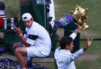 WIMBLEDON, ENGLAND - JULY 05:  Andy Roddick of USA looks despondent as Roger Federer of Switzerland celebrates with the trophy during the men's singles final match on Day Thirteen of the Wimbledon Lawn Tennis Championships at the All England Lawn Tennis and Croquet Club on July 5, 2009 in London, England. Federer won 5-7, 7-6, 7-6, 3-6, 16-14.  (Photo by Julian Finney/Getty Images)