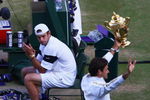 WIMBLEDON, ENGLAND - JULY 05:  Andy Roddick of USA looks despondent as Roger Federer of Switzerland celebrates with the trophy during the men's singles final match on Day Thirteen of the Wimbledon Lawn Tennis Championships at the All England Lawn Tennis and Croquet Club on July 5, 2009 in London, England. Federer won 5-7, 7-6, 7-6, 3-6, 16-14.  (Photo by Julian Finney/Getty Images)