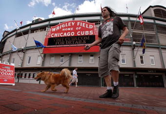 CHICAGO - JULY 6:  Pedestrians walk in front of Wrigley Field, home of the Chicago Cubs, July 6, 2009 in Chicago, Illinois. The Tribune Company, which owns the team and the ballpark has reached a deal, reported to be worth around $900 million, to sell both to the Ricketts family, which built its fortune through TD Ameritrade Holding Corp. The Tribune Company, which is operating under Chapter 11 bankruptcy, will need court approval as well as approval from Major League Baseball for the sale to be completed.  (Photo by Scott Olson/Getty Images)