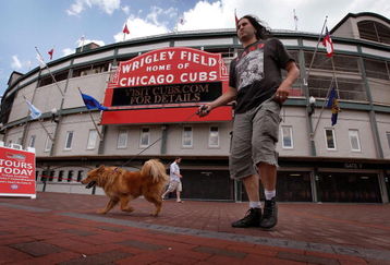 CHICAGO - JULY 6:  Pedestrians walk in front of Wrigley Field, home of the Chicago Cubs, July 6, 2009 in Chicago, Illinois. The Tribune Company, which owns the team and the ballpark has reached a deal, reported to be worth around $900 million, to sell both to the Ricketts family, which built its fortune through TD Ameritrade Holding Corp. The Tribune Company, which is operating under Chapter 11 bankruptcy, will need court approval as well as approval from Major League Baseball for the sale to be completed.  (Photo by Scott Olson/Getty Images)