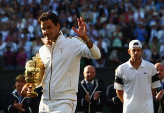 WIMBLEDON, ENGLAND - JULY 05:  Roger Federer of Switzerland celebrates victory with the trophy as Andy Roddick of USA (R) looks despondent after the men's singles final match on Day Thirteen of the Wimbledon Lawn Tennis Championships at the All England Lawn Tennis and Croquet Club on July 5, 2009 in London, England. Federer won 5-7, 7-6, 7-6, 3-6, 16-14.  (Photo by Clive Brunskill/Getty Images)