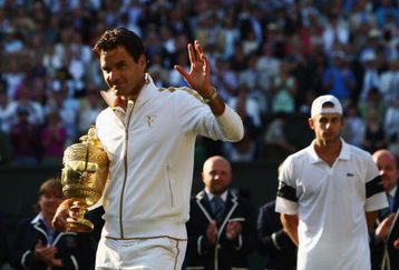 WIMBLEDON, ENGLAND - JULY 05:  Roger Federer of Switzerland celebrates victory with the trophy as Andy Roddick of USA (R) looks despondent after the men's singles final match on Day Thirteen of the Wimbledon Lawn Tennis Championships at the All England Lawn Tennis and Croquet Club on July 5, 2009 in London, England. Federer won 5-7, 7-6, 7-6, 3-6, 16-14.  (Photo by Clive Brunskill/Getty Images)