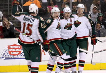 LOS ANGELES - MARCH 7:  (L to R) Andrew Brunette #15, Mikko Koivu #9, Owen Nolan #11, and Kurtis Foster #26 of the Minnesota Wild celebrate Nolan's first period goal against the Los Angeles Kings on March 7, 2009 at Staples Center in Los Angeles, California.   (Photo by Stephen Dunn/Getty Images)
