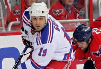 WASHINGTON - APRIL 28: Scott Gomez #19 of the New York Rangers skates the puck past Tom Poti #3   of the Washington Capitals during Game Seven of the Eastern Conference Quarterfinal Round of the 2009 Stanley Cup Playoffs on April 28, 2009 at the Verizon Center in Washington,  DC.  (Photo by Len Redkoles/Getty Images)