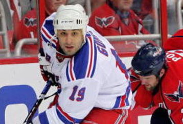 WASHINGTON - APRIL 28: Scott Gomez #19 of the New York Rangers skates the puck past Tom Poti #3   of the Washington Capitals during Game Seven of the Eastern Conference Quarterfinal Round of the 2009 Stanley Cup Playoffs on April 28, 2009 at the Verizon Center in Washington,  DC.  (Photo by Len Redkoles/Getty Images)