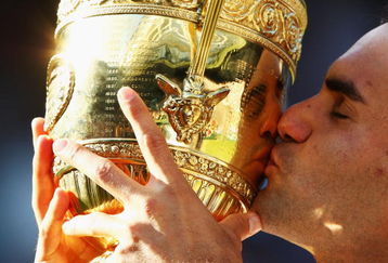 WIMBLEDON, ENGLAND - JULY 05:  Roger Federer of Switzerland kisses the trophy after victory during the men's singles final match against Andy Roddick of USA on Day Thirteen of the Wimbledon Lawn Tennis Championships at the All England Lawn Tennis and Croquet Club on July 5, 2009 in London, England. Federer won 5-7, 7-6, 7-6, 3-6, 16-14.  (Photo by Clive Brunskill/Getty Images)