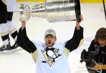 DETROIT - JUNE 12:  Philippe Boucher #43 of the Pittsburgh Penguins hoists the Stanley Cup overhead after Game Seven of the 2009 NHL Stanley Cup Finals against the Detroit Red Wings at Joe Louis Arena on June 12, 2009 in Detroit, Michigan. The Penguins defeated the Red Wings 2-1 in the seventh game to win the Stanley Cup Finals series 4 games to 3. (Photo by Harry How/Getty Images)