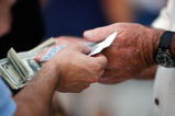 ST PETERSBURG, FL - OCTOBER 22:  A fan holds tickets and another holds money before the Philadelphia Phillies take on the Tampa Bay Rays during game one of the 2008 MLB World Series on October 22, 2008 at Tropicana Field in St. Petersburg, Florida.  (Photo by Jamie Squire/Getty Images)