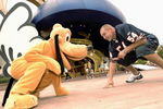 LAKE BUENA VISTA, FL - OCTOBER 11: In this handout photo Chicago Bears linebacker Brian Urlacher takes time out to line up with Pluto October 11, 2005 at the Disney-MGM Studios in Lake Buena Vista, Florida.  Urlacher was at Walt Disney World today to tape a commercial for 'ESPN The Weekend'  (Photo by Garth Vaughan/Disney via Getty Images)
