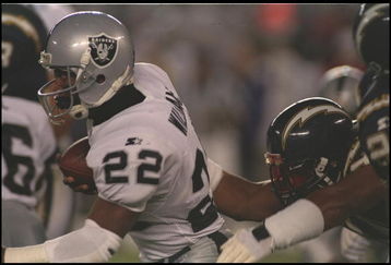 27 Nov 1995:  Running back Harvey Williams #22 of the Oakland Raiders attempts to break away from San Diego Charger defenders who cling as he sprints toward the endzone in Jack Murphy Stadium in San Diego, California.  The Chargers defeated the Raiders 12