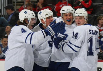 NEWARK, NJ - APRIL 07: Christian Hanson #20 (3rd from left) of the Toronto Maple Leafs scores his first NHL goal at 15:56 of the first period against Martin Brodeur #30 of the New Jersey Devils on April 7, 2009 at the Prudential Center in Newark, New Jersey. He is joined by (L-R) Jeff Finger #4, Tomas Kaberle #7 and Matt Stajan #14. (Photo by Bruce Bennett/Getty Images)