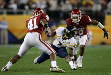 GLENDALE, AZ - JANUARY 02:  Noel Devine #7 of the West Virginia Mountaineers tries to elude Darien Williams #41 and Dominique Franks #15 of the Oklahoma Sooners after gaining 13-yards on a pass reception in the first quarter at the Tostito's Fiesta Bowl at University of Phoenix Stadium January 2, 2008 in Glendale, Arizona.  (Photo by Doug Pensinger/Getty Images)