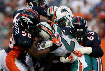 DENVER - NOVEMBER 02:  Running back Ronnie Brown #23 of the Miami Dolphins is stopped by defensive tackle Dewayne Robertson #63 and linebacker Nate Webster #58 of the Denver Broncos during NFL action at Invesco Field at Mile High on November 2, 2008 in Denver, Colorado. The Dolphins defeated the Broncos 26-17.  (Photo by Doug Pensinger/Getty Images)