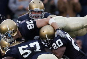 SOUTH BEND, IN - OCTOBER 13:  Members of the Notre Dame Fighting Irish including John Ryan #90, Dwight Stephenson #57 and Terrail Lambert #20 are called for a penalty for excessive celebration as they jump on teammate Brian Smith after Smith intercepted a pass and ran for a touchdown against the Boston College Eagles on October 13, 2007 at Notre Dame Stadium in South Bend, Indiana. Boston College defeated Notre Dame 27-14.  (Photo by Jonathan Daniel/Getty Images)