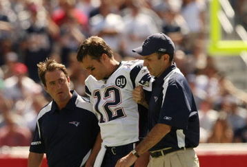 FOXBORO, MA - SEPTEMBER 7:  Quarterback Tom Brady #12 of the New England Patriots is helped off the field by trainers after he sustained an injury to his left knee in the first quarter against the Kansas City Chiefs at Gillette Stadium September 7, 2008 in Foxboro, Massachusetts.  (Photo by Elsa/Getty Images)