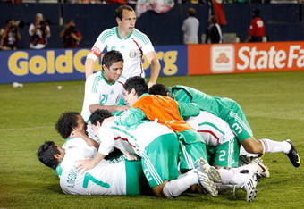 CHICAGO - JULY 23:  Players from Mexico pile on Carlos Vela #11 and Guillermo Ochoa #1 after Vela scored on the final attempt of the shoot out to win against Costa Rica during their CONCACAF Cup Semifinal match at Soldier Field on July 23, 2009 in Chicago, Illinois.  (Photo by Brian Kersey/Getty Images)