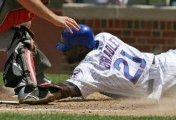 CHICAGO - JULY 26: Milton Bradley #21 of the Chicago Cubs is safe at home plate after sliding under the tag of Craig Tatum #30 of the Cincinnati Reds on July 26, 2009 at Wrigley Field in Chicago, Illinois. The Cubs defeated the Reds 5-2. (Photo by Jonathan Daniel/Getty Images)