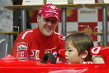 TOKYO - OCTOBER 8:  Michael Schumacher of Germany and Ferrari poses on Stage with a local child during an appearance at the Showa Shell headquarters on October 8, 2003 in Tokyo, Japan. (Photo by Mark Thompson/Getty Images).