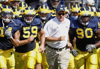 ANN ARBOR, MI - AUGUST 30:  Head coach Rich Rodriguez of the Michigan Wolverines leads his team onto the field between Tim Jamison #90 and Sean Griffin #59 prior to playing the Utah Utes on August 30, 2008 at Michigan Stadium in Ann Arbor, Michigan.  (Photo by Gregory Shamus/Getty Images)