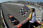 LONG POND, PA - AUGUST 03:  Denny Hamlin, driver of the #11 Federal Express Toyota, comes to the finish line to take the checkered flag from NASCAR flagman Rick Monroe as he took victory in the NASCAR Sprint Cup Series Sunoco Red Cross Pennsylvania 500 at the Pocono Raceway on August 3, 2009 in Long Pond, Pennsylvania.  (Photo by Doug Pensinger/Getty Images)