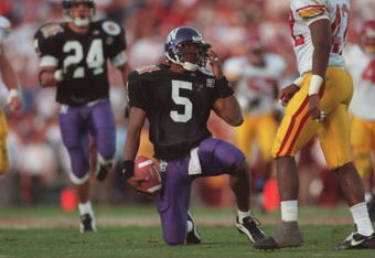 1 Jan 1996:  Running back D'Wayne Bates #5 of the Northwestern Wildcats reaches for his helmet as he attempts to remove a clump of grass from his face mask following a carry in the Wildcats 41-32 loss to the USC Trojans in the 1996 Rose Bowl game held at