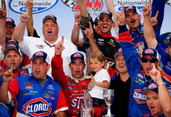 WATKINS GLEN, NY - AUGUST 08:  Marcos Ambrose (C), driver of the #47 STP Toyota, poses with his team in victory lane after winning the NASCAR Nationwide Series Zippo 200 at Watkins Glen International on August 8, 2009 in Watkins Glen, New York.  (Photo by Rusty Jarrett/Getty Images for NASCAR)