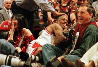 7 Jun 1996:  Dennis Rodman of the Chicago Bulls gets a pat on the head from a fan after crashing into photographers on the sidelines during third quarter action of game two of the NBA Finals at the United Center in Chicago, Illinois. The Bulls lead the se
