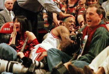 7 Jun 1996:  Dennis Rodman of the Chicago Bulls gets a pat on the head from a fan after crashing into photographers on the sidelines during third quarter action of game two of the NBA Finals at the United Center in Chicago, Illinois. The Bulls lead the se