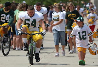 GREEN BAY, WI - AUGUST 03: Andrew Hartline #64 of the Green Bay Packers rides a bike to practice as a young fan carries his helmut during summer training camp on August 3, 2009 at the Ray Nitschke Field in Green Bay, Wisconsin. (Photo by Jonathan Daniel/Getty Images)