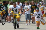 GREEN BAY, WI - AUGUST 03: Andrew Hartline #64 of the Green Bay Packers rides a bike to practice as a young fan carries his helmut during summer training camp on August 3, 2009 at the Ray Nitschke Field in Green Bay, Wisconsin. (Photo by Jonathan Daniel/Getty Images)