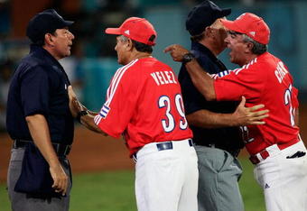 ATHENS - AUGUST 25:  Umpire Willie Rodriguez #3, R,  holds back coach Carlos Cepero #22, R, of Cuba as manager Higinio Velez #39 argues a call with home plate umpire Don Gilbert #15, L, against Australia in the gold medal baseball game on August 25, 2004 during the Athens 2004 Summer Olympic Games at the Baseball Centre in the Helliniko Olympic Complex in Athens, Greece.Cepero and Velez were arguing after Gilbert threw Cepero out of the game. (Photo by Donald Miralle/Getty Images)