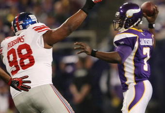 MINNEAPOLIS - DECEMBER 28:   Tarvaris Jackson #7 of the Minnesota Vikings passes under pressure from Fred Robbins #98 of the New York Giants on December 28, 2008 at the Hubert H. Humphrey Metrodome in Minneapolis, Minnesota. The Vikings defeated the Giants 20-19. (Photo by Elsa/Getty Images)