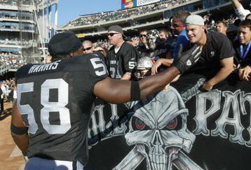 OAKLAND, CA - SEPTEMBER 26:  Napoleon Harris #58 of the Oakland Raiders greets fans in the stands as he enters the stadium before the game against the Tampa Bay Buccaneers on September 26, 2004 at Network Associates Coliseum in Oakland, California.  The Raiders defeated the Buccaneers 30-20.  (Photo by Stephen Dunn/Getty Images)