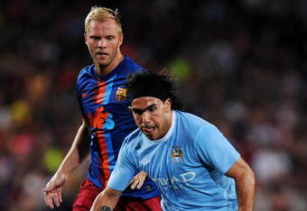 BARCELONA, SPAIN - AUGUST 19:  Carlos Tevez (R) of Manchester City duels for the ball with Eidur Gudjohnsen of Barcelona during the Joan Gamper Trophy match between Barcelona and Manchester City at the Camp Nou Stadium on August 19, 2009 in Barcelona, Spain.  (Photo by Jasper Juinen/Getty Images)