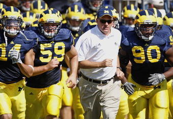 ANN ARBOR, MI - AUGUST 30:  Head coach Rich Rodriguez of the Michigan Wolverines leads his team onto the field between Tim Jamison #90 and Sean Griffin #59 prior to playing the Utah Utes on August 30, 2008 at Michigan Stadium in Ann Arbor, Michigan.  (Photo by Gregory Shamus/Getty Images)