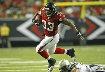 ATLANTA - AUGUST 29:  Running back Michael Turner #33 of the Atlanta Falcons is tripped up by cornerback Antoine Cason #20 of the San Diego Chargers during the game at the Georgia Dome on August 29, 2009 in Atlanta, Georgia.  The Falcons beat the Chargers 27-24.  (Photo by Mike Zarrilli/Getty Images)