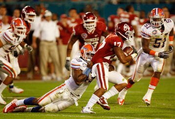 MIAMI - JANUARY 08:  Mossis Madu #17 of the Oklahoma Sooners gets tackled by Jermaine Cunningham #49 of the Florida Gators during the FedEx BCS National Championship Game at Dolphin Stadium on January 8, 2009 in Miami, Florida.  (Photo by Eliot J. Schechter/Getty Images)