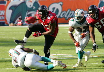 MIAMI - NOVEMBER 6:  Tight end Alge Crumpler #83 of the Atlanta Falcons jumps over cornerback Travis Daniels #21 of the Miami Dolphins after a pass reception on November 6, 2005 at Dolphins Stadium in Miami, Florida. The Falcons defeated the Dolphins 17-10. (Photo by Paul Spinelli/Getty Images)