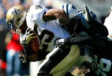 CHARLOTTE, NC - OCTOBER 19:  Running back Reggie Bush #25 of the New Orleans Saints is tackled by Na'il Diggs #53 and Tyler Brayton #96 of the Carolina Panthers during the game at Bank of America Stadium on October 19, 2008 in Charlotte, North Carolina.  (Photo by Kevin C. Cox/Getty Images)