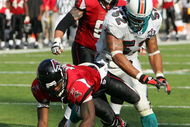 MIAMI - NOVEMBER 6:  Linebacker Channing Crowder #52 of the Miami Dolphins knocks down quarterback Michael Vick #7 of the Atlanta Falcons on November 6, 2005 at Dolphins Stadium in Miami, Florida. The Falcons defeated the Dolphins 17-10. (Photo by Paul Spinelli/Getty Images)