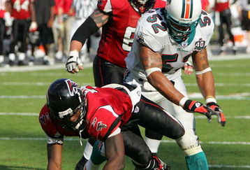 MIAMI - NOVEMBER 6:  Linebacker Channing Crowder #52 of the Miami Dolphins knocks down quarterback Michael Vick #7 of the Atlanta Falcons on November 6, 2005 at Dolphins Stadium in Miami, Florida. The Falcons defeated the Dolphins 17-10. (Photo by Paul Spinelli/Getty Images)