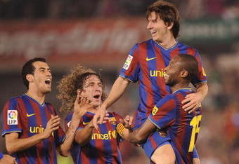 SANTANDER, SPAIN - SEPTEMBER 22:  Lionel Messi of Barcelona is lifted up by Seydou Keita after scoring Barcelona's fourth goal against Racing Santander during the La Liga match between Racing Santander and Barcelona at El Sardinero stadium on September 22, 2009 in Santander, Spain.  (Photo by Denis Doyle/Getty Images)
