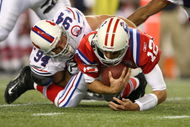 FOXBORO, MA - SEPTEMBER 14:  Quarterback Tom Brady #12 of the New England Patriots is sacked by Aaron Schobel #94 of the Buffalo Bills on September 14, 2009 at Gillette Stadium in Foxboro, Massachusetts. (Photo by Elsa/Getty Images)