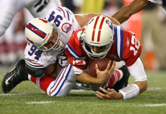 FOXBORO, MA - SEPTEMBER 14:  Quarterback Tom Brady #12 of the New England Patriots is sacked by Aaron Schobel #94 of the Buffalo Bills on September 14, 2009 at Gillette Stadium in Foxboro, Massachusetts. (Photo by Elsa/Getty Images)